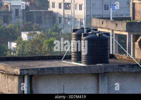 Zwei schwarze, große Kunststoff-Wassertanks (Reservoirs), die auf dem Dach eines Wohnhauses in Bangladesch installiert sind. Wird für Haushaltswasser verwendet Stockfoto