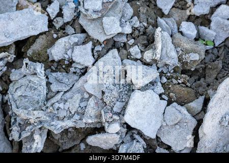 Nahaufnahme, abstrakte Hintergrundstruktur eines großen, rauen Haufens gebrochener Baumaterialien, einschließlich getrocknetem Putz und zerbrochenem Zement mit Stücken Stockfoto