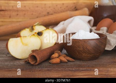 Backzutaten auf einem rustikalen Holztisch mit geschnittenen Äpfeln, Zimtstangen und Walnüssen, die die ersten Schritte der Zubereitung einer HO darstellen Stockfoto
