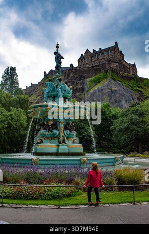 Edinburgh, Schottland: Ein Mädchen vor dem Ross Fountain, 1872 gusseiserner Brunnen in den öffentlichen Parks der West Princes Street Gardens, mit dem Edinburgh Castle Stockfoto