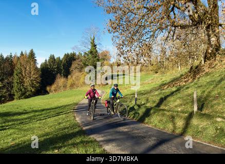 Nettes aktives Seniorenpaar, das am warmen Herbsttag Baden-Wuerttem in unmittelbarer Nähe der Stadt Isny im schwäbischen Allgäu mit dem E-Mountainbike fährt Stockfoto
