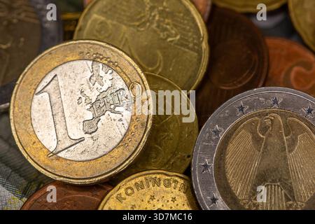 Berlin, Deutschland. November 2025. Auf einem Tisch befinden sich Münzen verschiedener Euro-Stückelungen, darunter ein- und zwei-Euro- und Cent-Stücke. Teile der Euro-Banknoten sind im Hintergrund zu sehen. Quelle: Fernando Gutierrez-Juarez/dpa/Alamy Live News Stockfoto