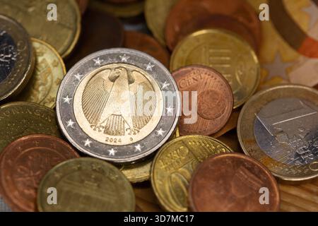 Berlin, Deutschland. November 2025. Auf einem Tisch befinden sich Münzen verschiedener Euro-Stückelungen, darunter ein- und zwei-Euro- und Cent-Stücke. Teile der Euro-Banknoten sind im Hintergrund zu sehen. Quelle: Fernando Gutierrez-Juarez/dpa/Alamy Live News Stockfoto