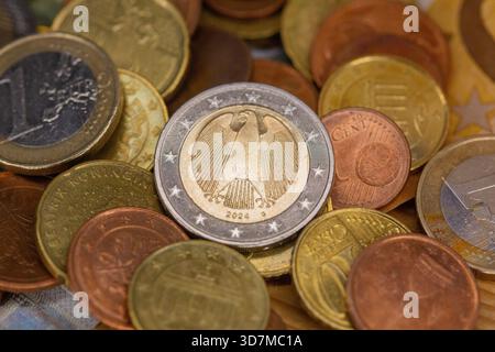Berlin, Deutschland. November 2025. Auf einem Tisch befinden sich Münzen verschiedener Euro-Stückelungen, darunter ein- und zwei-Euro- und Cent-Stücke. Teile der Euro-Banknoten sind im Hintergrund zu sehen. Quelle: Fernando Gutierrez-Juarez/dpa/Alamy Live News Stockfoto