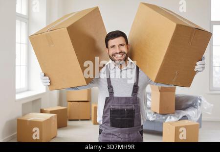 Ein glücklicher Mann aus der Umzugsfirma, der große Pappschachteln hält, im Haus steht Stockfoto