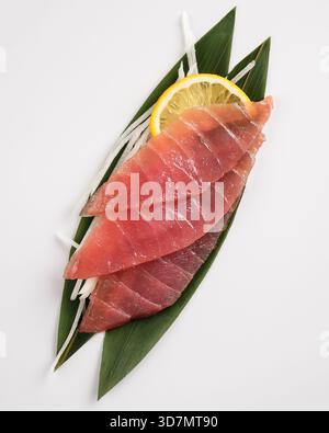 Hochwertiges rohes Sashimi mit Zitronenakzent auf minimalem Hintergrund Stockfoto