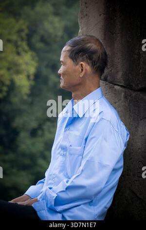 Sitzender Mann in blauem Hemd in Siem Reap, Kambodscha Stockfoto