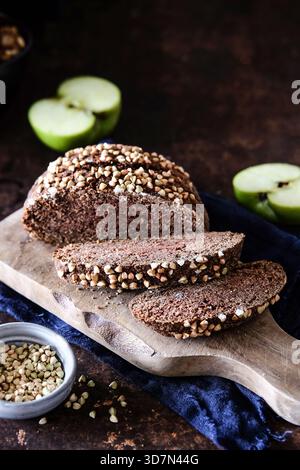 Handgefertigter Brotlaib mit frischen Apfelscheiben auf Holzoberfläche Stockfoto