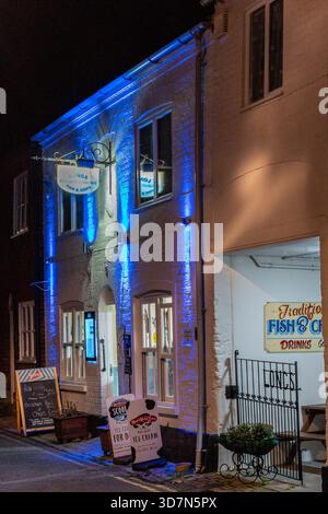 Traditioneller britischer Fisch- und Chips-Shop bei Nacht – zu Weihnachten in Bridport, Dorset, mit blauem Licht an der Küste Stockfoto