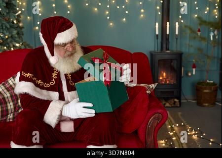 Der Weihnachtsmann liest Kinderbriefe auf dem Computer und bestellt online Stockfoto