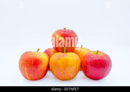 Sechs rote Äpfel in Form einer Pyramide, bedeckt mit Wassertröpfchen. Stockfoto
