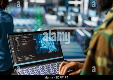 Spezialist für Black Army-Technologie bei der Fehlerbehebung für militärische pc-Systeme im Rechenzentrum, Netzwerke mit Laptop. Soldat im Serverraum der Kommandozentrale mit Notebook. Stockfoto