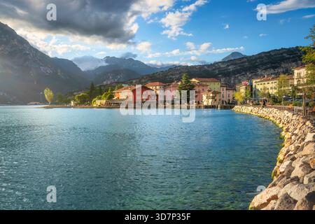 Blick auf die Ufergebäude von Torbole sul Garda, Trentino, eingebettet am Nordufer des Gardasees. Die felsige Küste wird von hohen Gipfeln eingerahmt Stockfoto