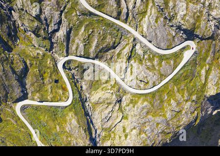 Aus der Vogelperspektive auf eine gewundene Straße, die sich durch das zerklüftete Gelände schlängelt, mit grünen Vegetationsflächen, die sich an den Felsen hängen, Geiranger, mehr oder Romsdal, Stockfoto