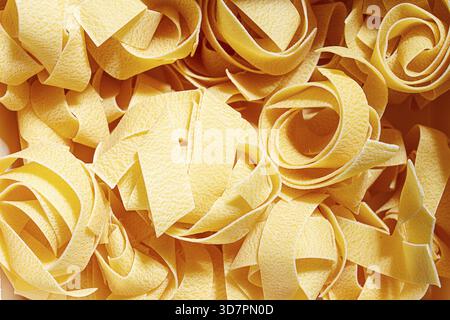 Rohe Pappardelle Nudeln, Nudelnester, in einem Papierkarton, hartes Licht, Blick von oben, keine Leute Stockfoto