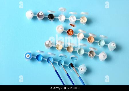 Farben und Pinsel zum Malen nach Zahlen auf blauem Hintergrund Stockfoto