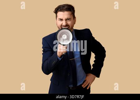 Wütender Geschäftsmann, der in Megaphon auf beigefarbenem Hintergrund schreit Stockfoto