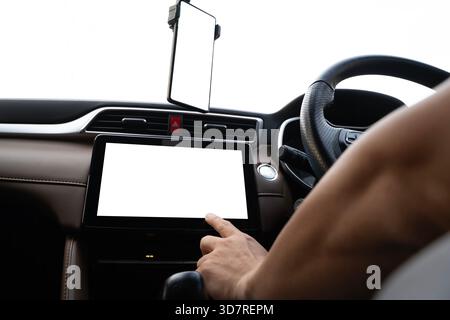 Nahaufnahme einer Hand, die mit einem Touchscreen und Smartphone in einem modernen Fahrzeuginnenraum interagiert, wobei digitale Steuerung, mobile Konnektivität, Stockfoto