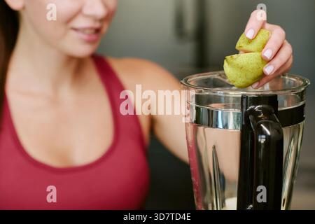 Junge Erwachsene Kaukasierin bereitet gesundes Frühstück Smoothie am Morgen vor Stockfoto