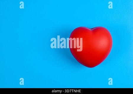 Rotes, herzförmiges Objekt auf hellblauem Hintergrund, das Liebe und Emotionen durch kräftigen Farbkontrast und einfache visuelle Fokussierung symbolisiert. Stockfoto