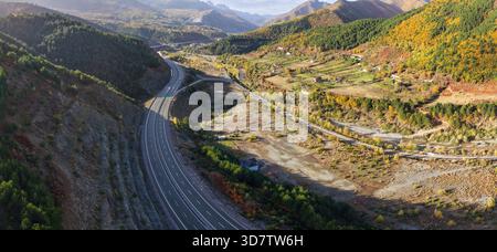 Herbstlicher Blick auf das Dorf Zall-Xhuxhë und die Autobahn A1, die sich durch die farbenfrohen Berge des Bezirks Mirditë schlängelt. Stockfoto