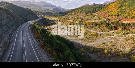 Herbstlicher Blick auf das Dorf Zall-Xhuxhë und die Autobahn A1, die sich durch die farbenfrohen Berge des Bezirks Mirditë schlängelt. Stockfoto