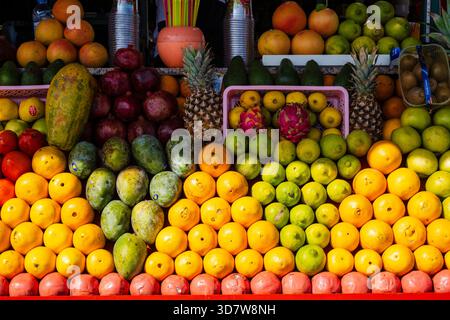 Lebhafte Präsentation verschiedener tropischer Früchte in bunten Reihen an einem Marktstand. Marrakesch, Marokko Stockfoto