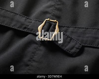 Nahaufnahme einer Messingschnalle auf dunklem Stoff mit detaillierten Nähten. Stockfoto