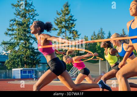 Die Athleten sprinten über die Ziellinie auf einer Outdoor-Strecke mit Bäumen im Hintergrund. WA, USA Stockfoto