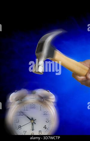 Hammer schlägt den Wecker vor blauem Hintergrund Stockfoto