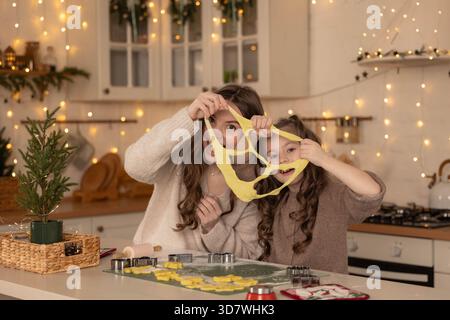 Mutter und Tochter haben Spaß mit Keksenteig in der festlichen Küche Stockfoto