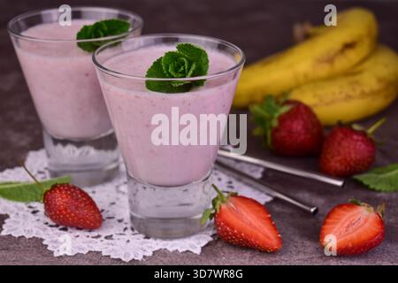 Erdbeer-Bananen-Milchshake in Gläsern auf grauem Hintergrund. Stockfoto