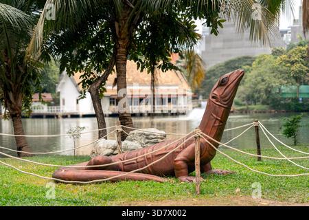 Eine rötlich-braune Statue eines Varanus salvator ruht auf dem Gras eines Parks in Bangkok. Sie ist die zweitgrößte Echsenart nach dem Komodo-Drachen. Stockfoto