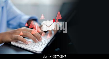Hände tippen auf der Tastatur mit E-Mail-Warnsymbolen, Phishing-Warnsymbolen und digitalen Risikobenachrichtigungen, die Cybersicherheitsbedrohungen und Onlin darstellen Stockfoto
