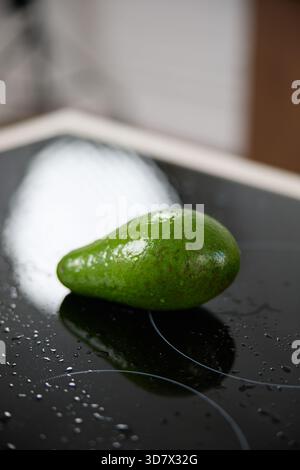 Eine frische grüne Avocado liegt auf einem Glasherd Stockfoto
