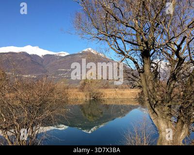 Ein Berg, der sich in den ruhigen Gewässern des Comer Sees in der Nähe von Colico, Lombardei, Italien spiegelt. Stockfoto