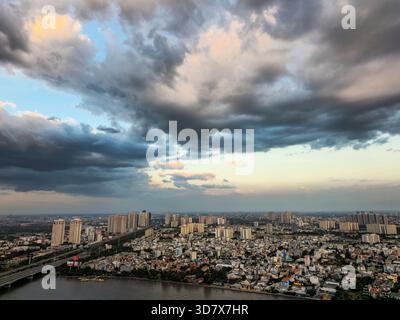 Stadt mit einem großen Gewässer im Hintergrund. Der Himmel ist bewölkt und die Sonne untergeht Stockfoto