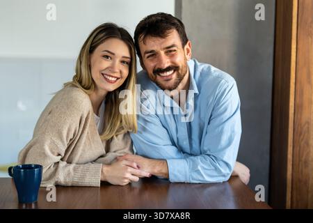 Glückliches und vielseitiges Paar, das einen fröhlichen Moment zu Hause teilt, zusammen umgeht und lächelt Stockfoto