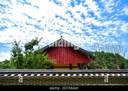 Ein rotes Gebäude mit rotem Dach. Das Dach ist mit Fliesen bedeckt. Das Gebäude ist von Bäumen umgeben Stockfoto