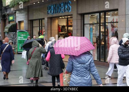 Dublin, Irland - 26. November 2025 - Eine Frau mit einem pinkfarbenen Schirm geht in Richtung Penneys Kleiderladen in der O'Connell Street im Stadtzentrum von Dublin und zeigt Straßenszenen in der irischen Hauptstadt Stockfoto