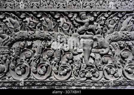 Eine Wand mit vielen Details und ein Mann, der auf einem Elefanten reitet. Der Elefant ist auf der rechten Seite der Wand Stockfoto