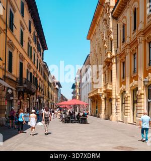 Pisa, Italien - 26. Juni 2025: Ein lebhafter Blick auf den Corso Italia zeigt Käufer und Fußgänger, die sich zwischen den warmen Fassaden und dem Café im Freien bewegen Stockfoto