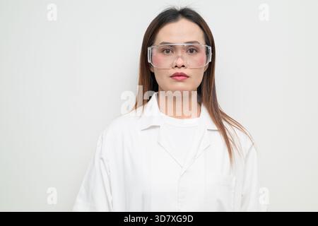 Studio-Porträt eines asiatischen Wissenschaftlers mit weißem Labormantel und Schutzbrille. Seriöser, professioneller Look geeignet für Labor, Forschung Stockfoto