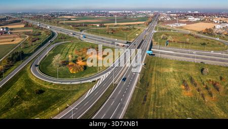 Autobahnkreuz Landschaft Herbst Aus Der Vogelperspektive. Drohnenfoto mit komplexer Straßeninfrastruktur mit Autos, grünen Feldern und Vorstadtbereichen während Stockfoto