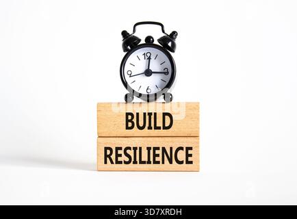 Symbol für Belastbarkeit erstellen. Holzklötze mit Wörtern sorgen für Widerstandsfähigkeit. Schöner weißer Hintergrund mit Wecker. Business- und Build Resilience-Konzept Stockfoto