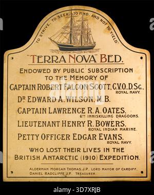 Plakette für das Bett, gestiftet zum Gedenken an Captain Scott und vier Besatzungsmitglieder, die bei der British Antarctic Expedition (1910) starben. Vom Hamadryad Hospital, Cardiff. c. 20. Jahrhundert. Messingtafel mit gewölbtem Kopf, mit dreiviertel vorderer Portionsgravur der Terra Nova zwischen dem ursprünglichen Moto und dem Namen des Stiftbetts. Obwohl sie zur Zeit der Expedition von Captain Scott fast dreißig Jahre alt war, wurde die Terra Nova wegen ihrer Eignung für die Arbeit im antarktischen Eis ausgewählt. Ihre Balken waren 14 Zoll dick, ihre Bögen waren 9 Fuß aus massivem Holz, und ihr Stiel war s Stockfoto