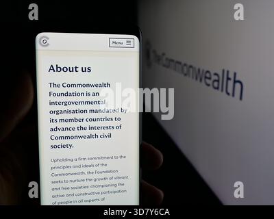 Stuttgart, Deutschland - 19.11.2025: Person, die ein Mobiltelefon hält, mit Webseite des Sekretariats der Institution Commonwealth auf dem Bildschirm vor dem Logo. Stockfoto