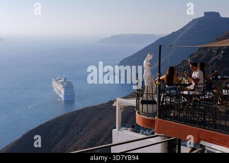 Santorin, GR - 4. September 2025: Die Gäste entspannen sich in einer Bar auf einer Klippe, genießen Getränke und blicken auf die Caldera und den Vulkan i Stockfoto