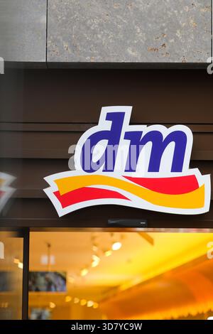 Bamberg, Deutschland 27. November 2025: Im Bild: Blick auf das Markenlogo einer dm Drogerie in der Bamberger Innenstadt. Die Aufnahme zeigt den Eingangsbereich des Einzelhandelsunternehmens, teilweise verzerrt durch Lichtreflexionen und Glasüberlagerungen. Neutrale Szene Stockfoto
