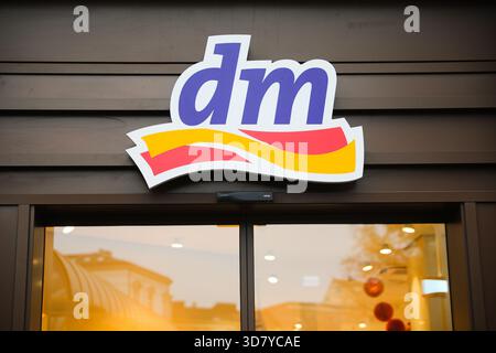 Bamberg, Deutschland 27. November 2025: Im Bild: Fassadenansicht mit dem Markenlogo einer dm Drogerie in der Bamberger Innenstadt. Das beleuchtete Schaufenster reflektiert die Gebäudestrukturen der Umgebung, innen Lichtreflexionen und Dekoration Stockfoto